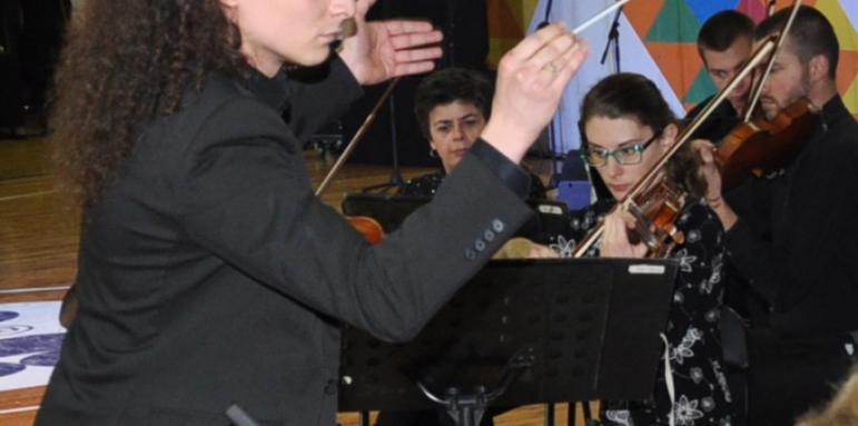 Млад диригент показва на деца цигулки и виоли
